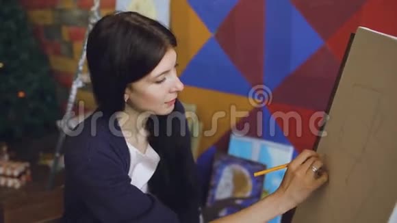 年轻的女画家用铅笔在画架画布上画画准备画画视频的预览图