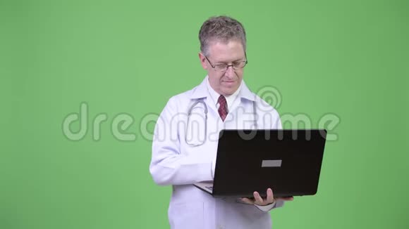 成熟男性医生在使用笔记本电脑时思考的肖像视频的预览图