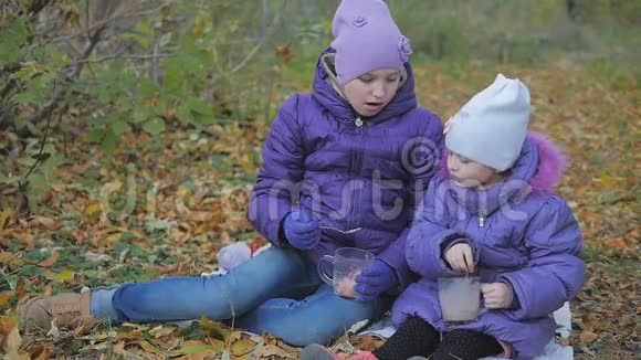 小女孩在新鲜空气中喝可可秋天公园慢动作视频的预览图