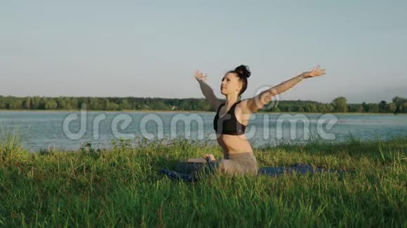 早上在湖边做瑜伽的女人日出时在莲花位置的美女视频的预览图