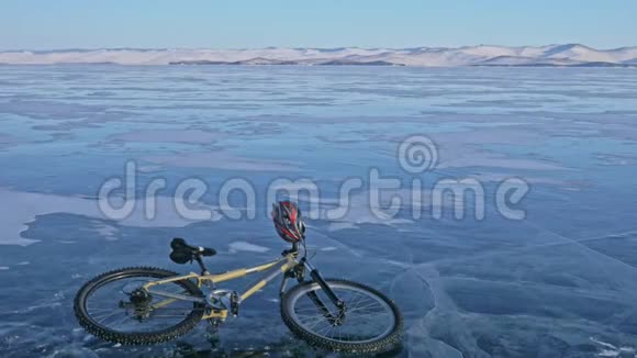 人和他的自行车在冰上骑自行车的人穿着灰色的羽绒服背包和头盔冰冻湖的冰视频的预览图