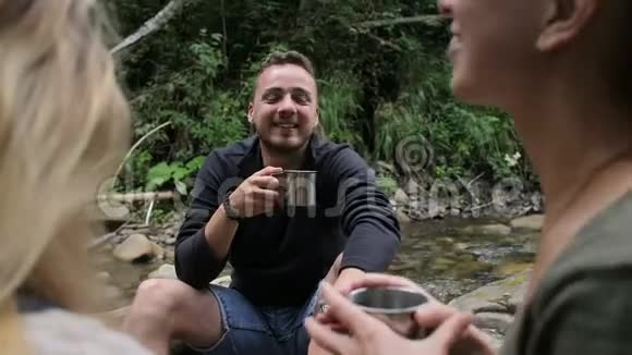 徒步旅行者在溪边的营地喝咖啡视频的预览图