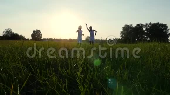 剪影儿童的身影男孩和女孩跳跃玩得开心跳舞在阳光的背景下拥抱视频的预览图