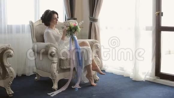 温柔的新娘坐在椅子上手里拿着结婚花束视频的预览图