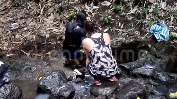 菲律宾农村社区缺乏公共供水系统公用设施迫使这些妇女甚至在污染的河流中洗澡和洗澡视频的预览图
