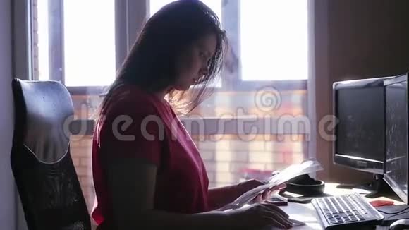 年轻女孩坐在桌子旁手里拿着纸仔细阅读慢动作视频的预览图