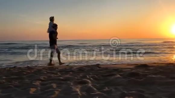 父亲和女儿在日出时沿着海滩散步视频的预览图