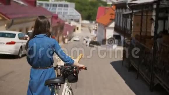一位挥舞着头发的女孩用花篮和面包在自行车上行走后景4ksteatam拍摄视频的预览图