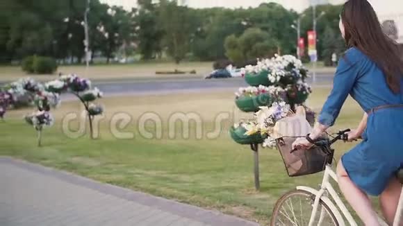 从侧面和背面看一个女孩骑着自行车在驾驶的汽车附近花在篮子里慢的稳定的镜头视频的预览图