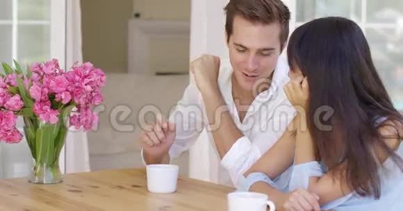 坐在餐桌上的一对快乐的混血成年夫妇视频的预览图
