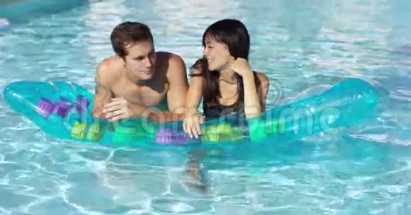 可爱的情侣在游泳池的浮动床垫上放松视频的预览图