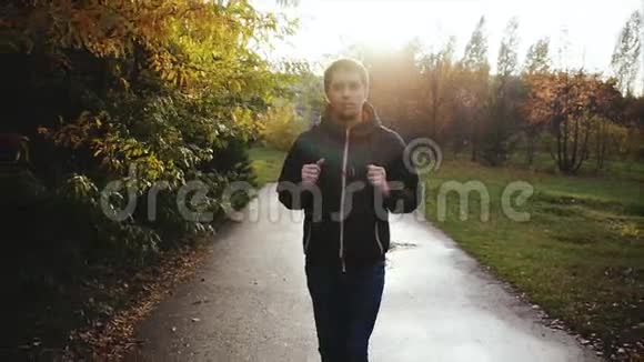 穿着黑色夹克在秋天公园散步的年轻人视频的预览图