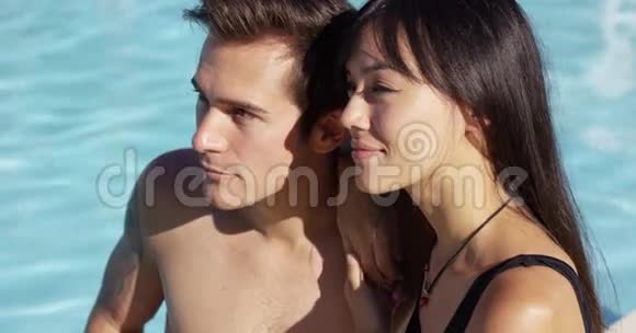 日光浴夫妇坐在游泳池旁边视频的预览图
