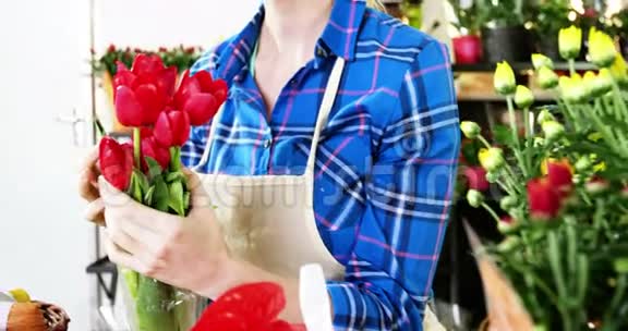 在花店里女花匠捧着一束红玫瑰视频的预览图
