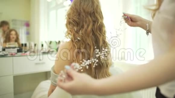 专业沙龙造型师美发师在金色波浪型女模特头上戴上珠宝发饰加西皇冠珍珠头饰视频的预览图