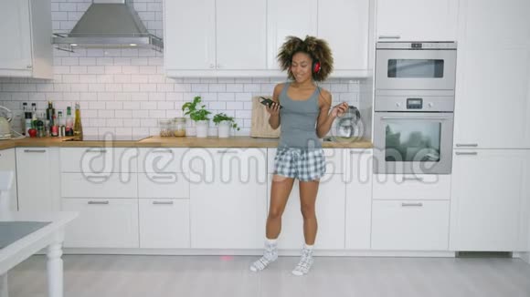 年轻女子在厨房用智能手机跳舞视频的预览图