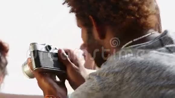 年轻人用老式照相机拍朋友的照片视频的预览图