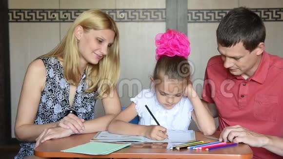 女学生和父母一起做家庭作业微笑着看着相框视频的预览图