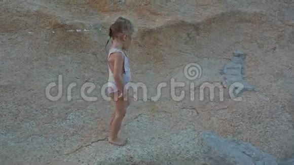 小女孩爬上海滩夕阳下的大光岩视频的预览图