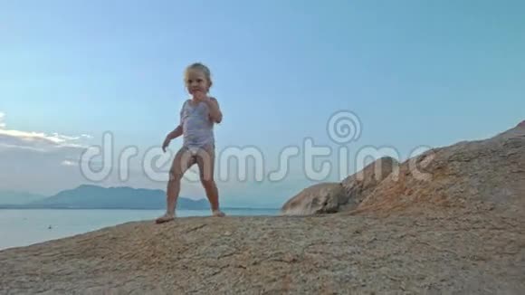 小女孩在海滩夕阳下爬上大光岩视频的预览图