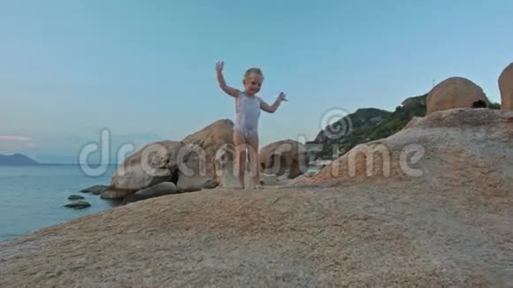 小女孩站在沙滩上的夕阳下的山顶浪手视频的预览图