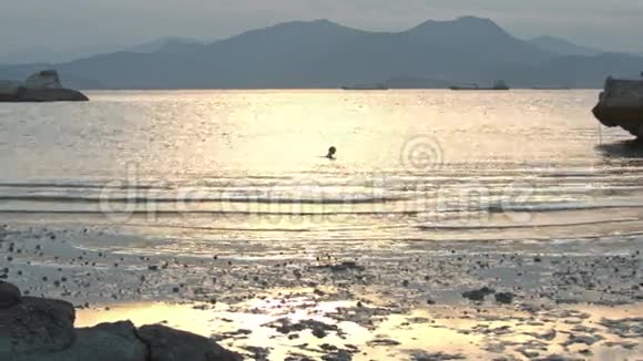 小女孩在海中游泳日落时的山径视频的预览图