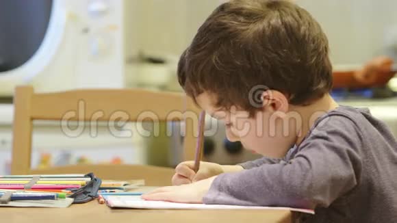 可爱的小男孩在家里的桌子旁画画视频的预览图