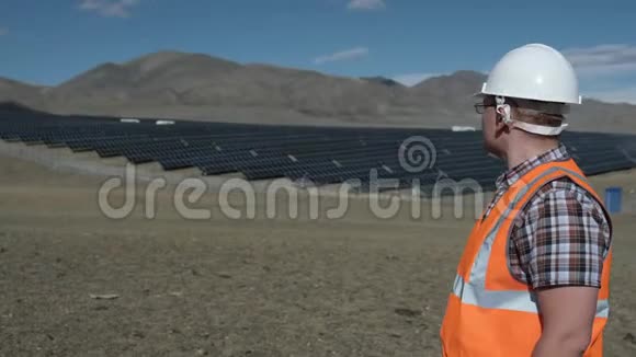戴着头盔和背心的工程师在沙漠中的太阳能电池板项目上工作视频的预览图