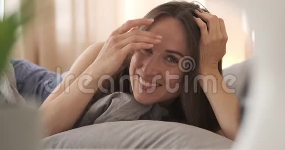 穿着睡衣躺在床上的快乐女人视频的预览图