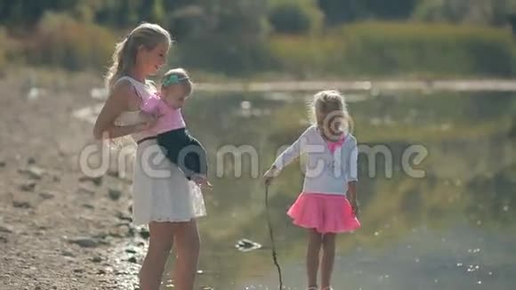 妈妈和她可爱的小女孩在湖边散步视频的预览图