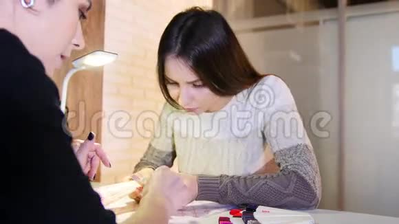 女孩选择指甲的颜色和质地在专业的美甲美容院滑块视频的预览图