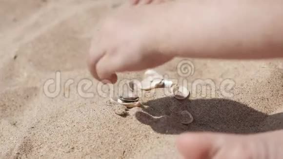 小可爱的女孩在海滩上玩沙子和贝壳在UHD关闭视频的预览图