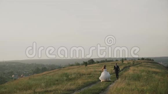 日落时在田野里的情人日落时分一群人在田野里跑来跑去快乐的一对微笑视频的预览图