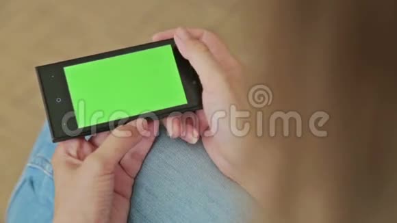 漂亮的女人拿着绿色屏幕显示和滚动的智能手机视频的预览图