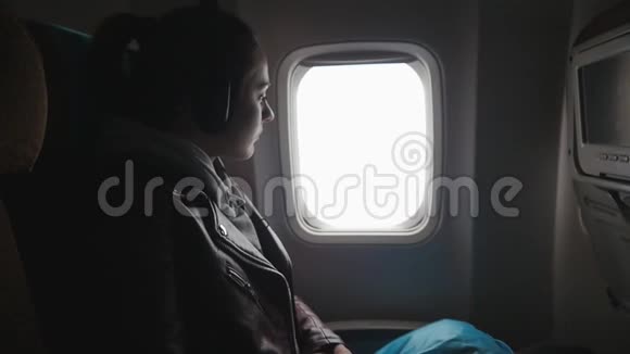 年轻女子乘飞机旅行坐在窗边欣赏风景视频的预览图