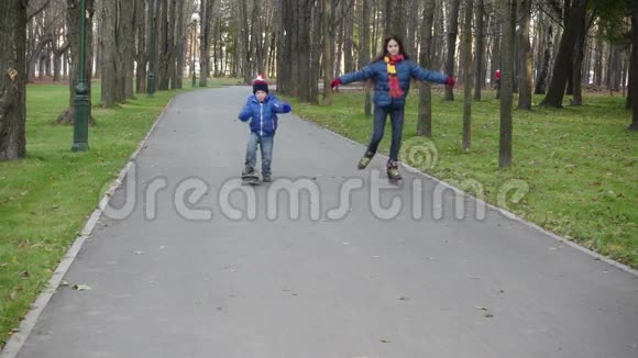 男孩和女孩骑着旱冰车和滑板在秋天的公园里视频的预览图