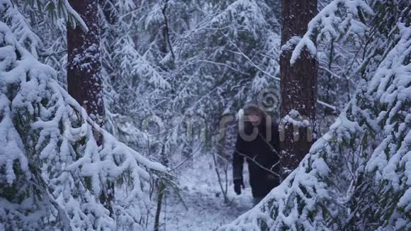 男子走雪冬季森林旅行者与背包在镜头前挥动他的手视频的预览图