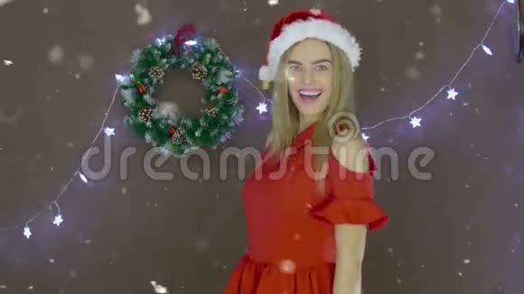 美丽的金发女孩穿着红色连衣裙戴着圣诞帽手里拿着黑板上写着圣诞快乐视频的预览图