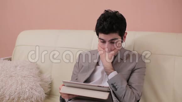 年轻的商人通过平板电脑仔细阅读课文视频的预览图