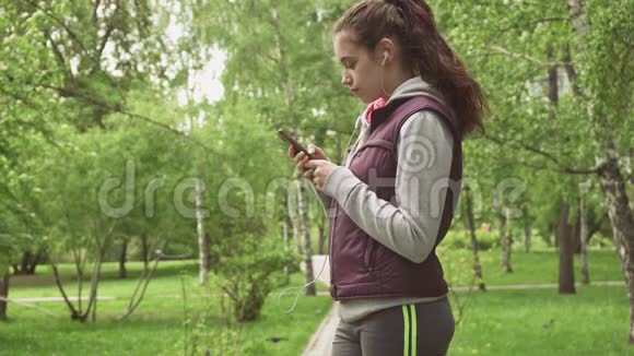 美丽的年轻女孩打开音乐开始慢跑女运动员在训练中听音乐慢慢慢慢视频的预览图