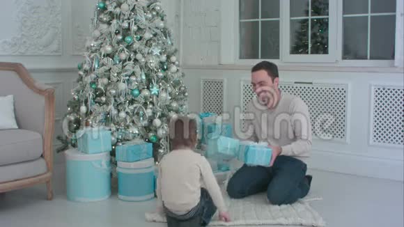 微笑的父亲和儿子在客厅里打开圣诞礼物视频的预览图