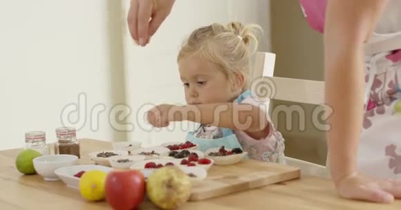看小孩的女人在松饼上撒糖果视频的预览图
