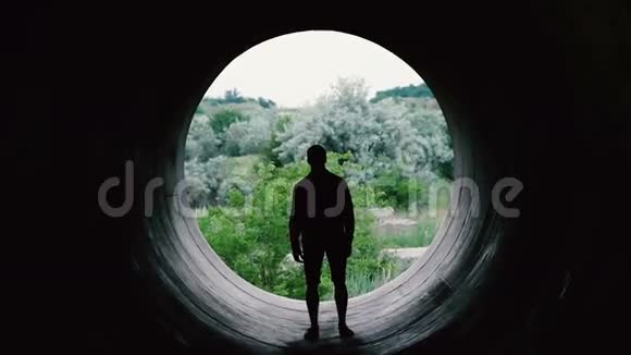 一个年轻人在一个巨大的洞的背景上接近相机的剪影视频的预览图