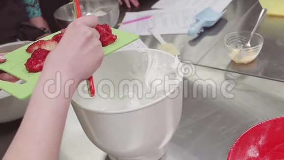 女性糖果师将切好的草莓放入搅拌碗中加入鲜奶油视频的预览图