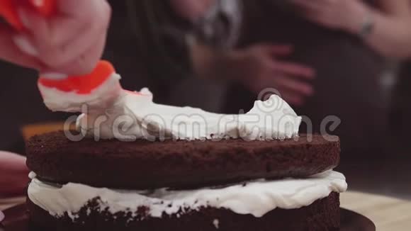 糖果手将鲜奶油涂在巧克力小蛋糕上视频的预览图