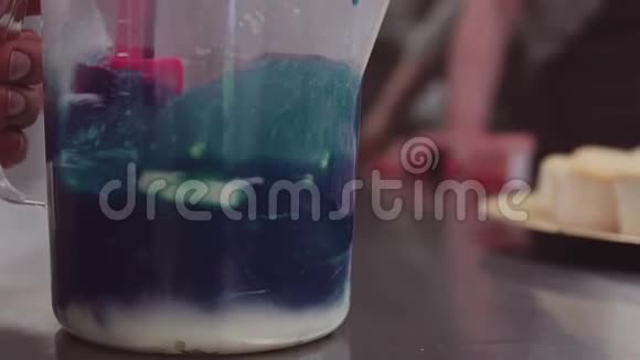 蓝色食用色素与鲜奶油混合在量杯中视频的预览图