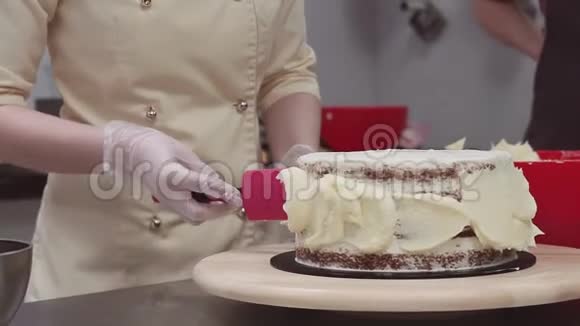 女糕点厨师手把鲜奶油涂在短海绵蛋糕上视频的预览图