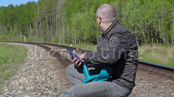 拄拐的残疾人坐在铁路上使用平板电脑视频的预览图