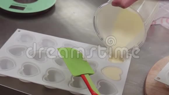 将奶饼从量杯中倒入塑料心形成型皿视频的预览图