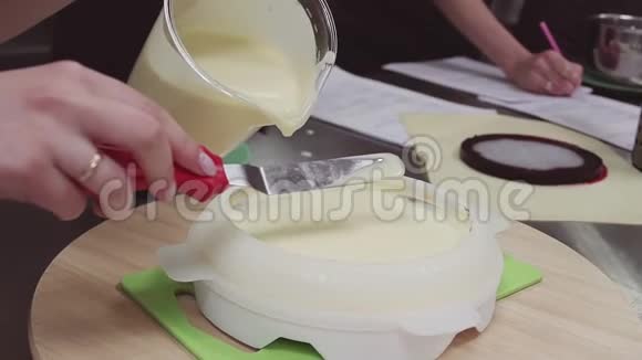 女糕点师将奶油蛋糕倒入糕点厨房的菜肴中视频的预览图